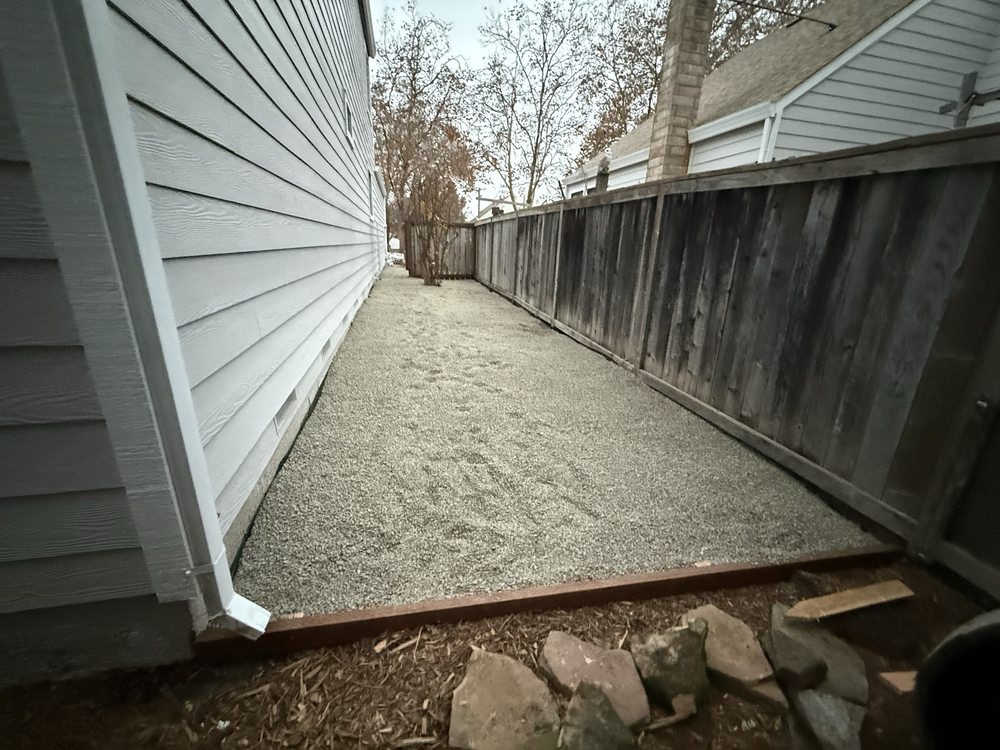 Neatly finished gravel side yard between a house and fence with redwood edging